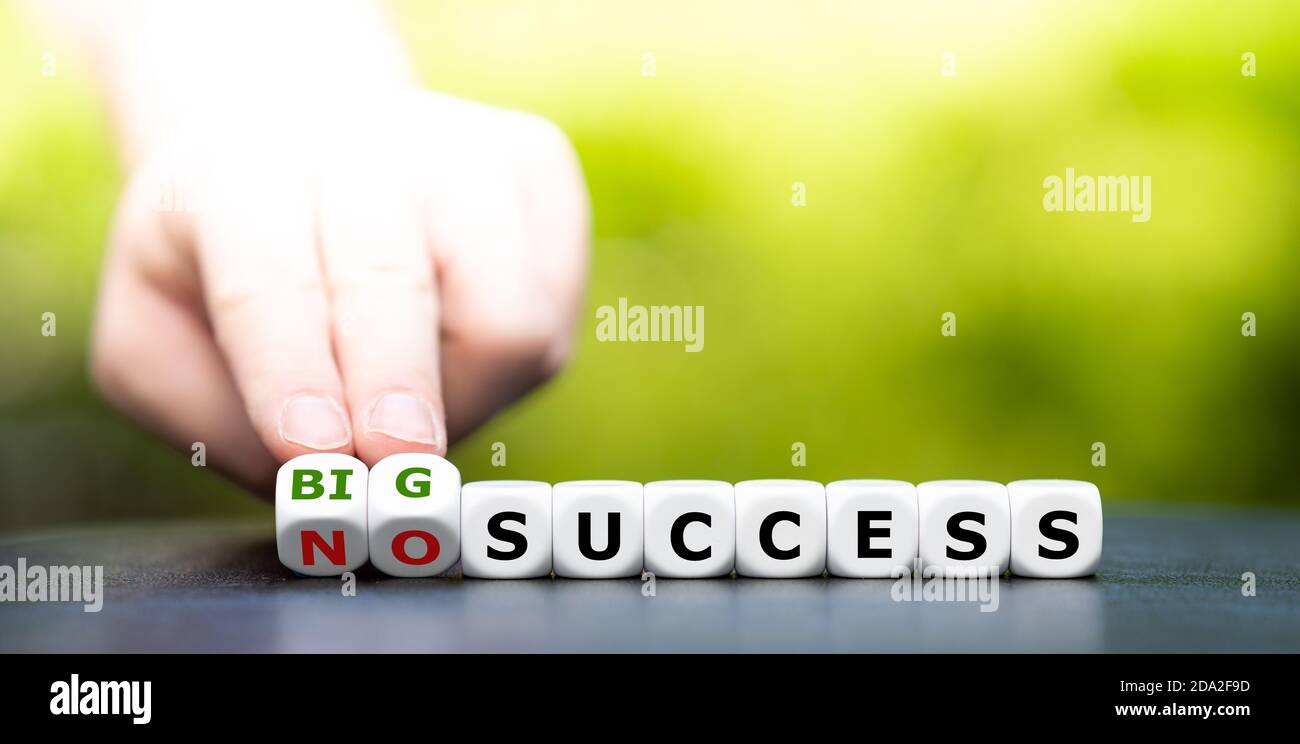 Hand turns dice an changes the expression "no success" to "big success". Stock Photo