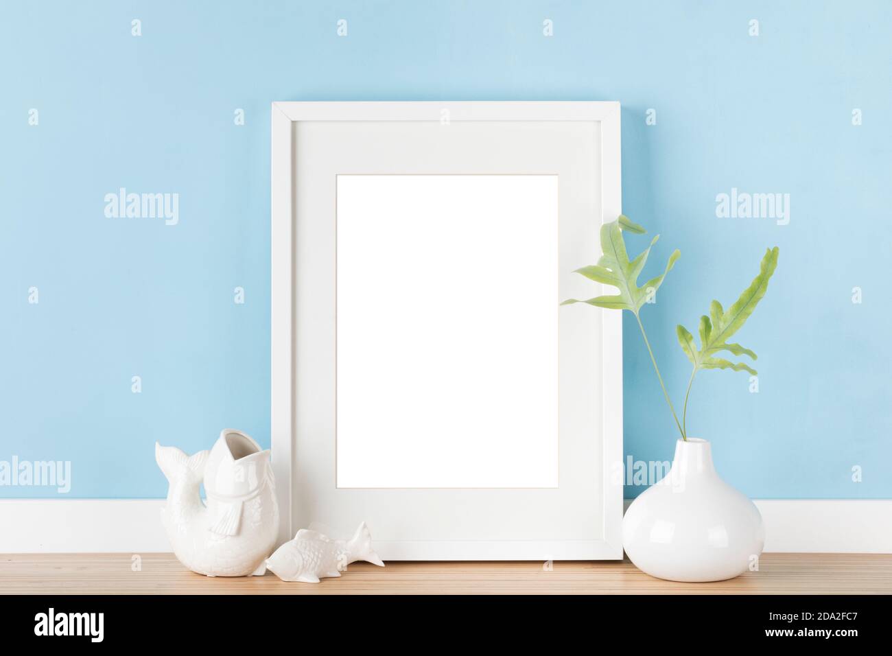 Elegant vertical picture frame with matte mockup, japanese decoration in front of blue wall. Blank image area masked with clipping path Stock Photo