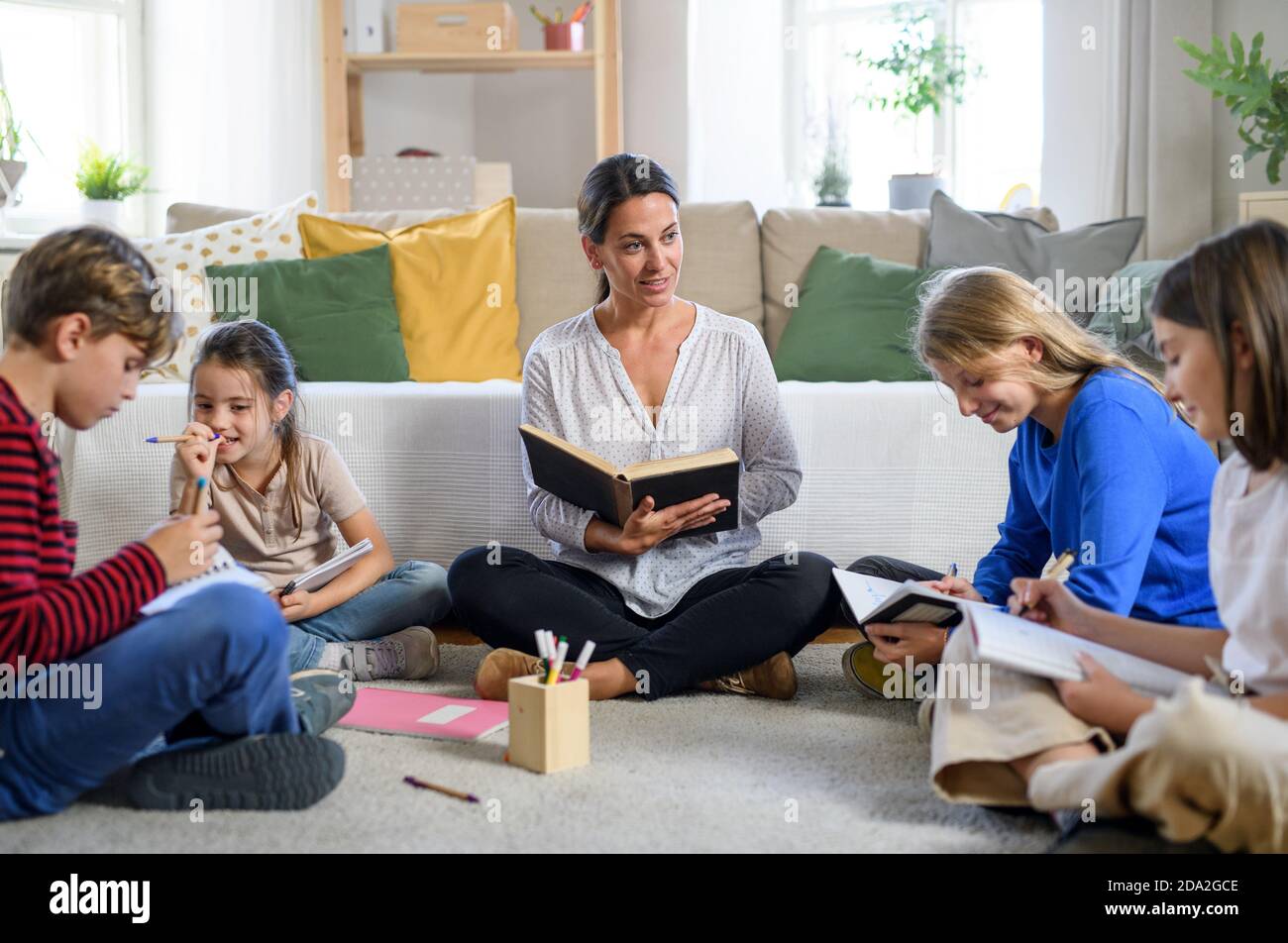 Group of homeschooling children with parent teacher studying indoors, coronavirus concept. Stock Photo