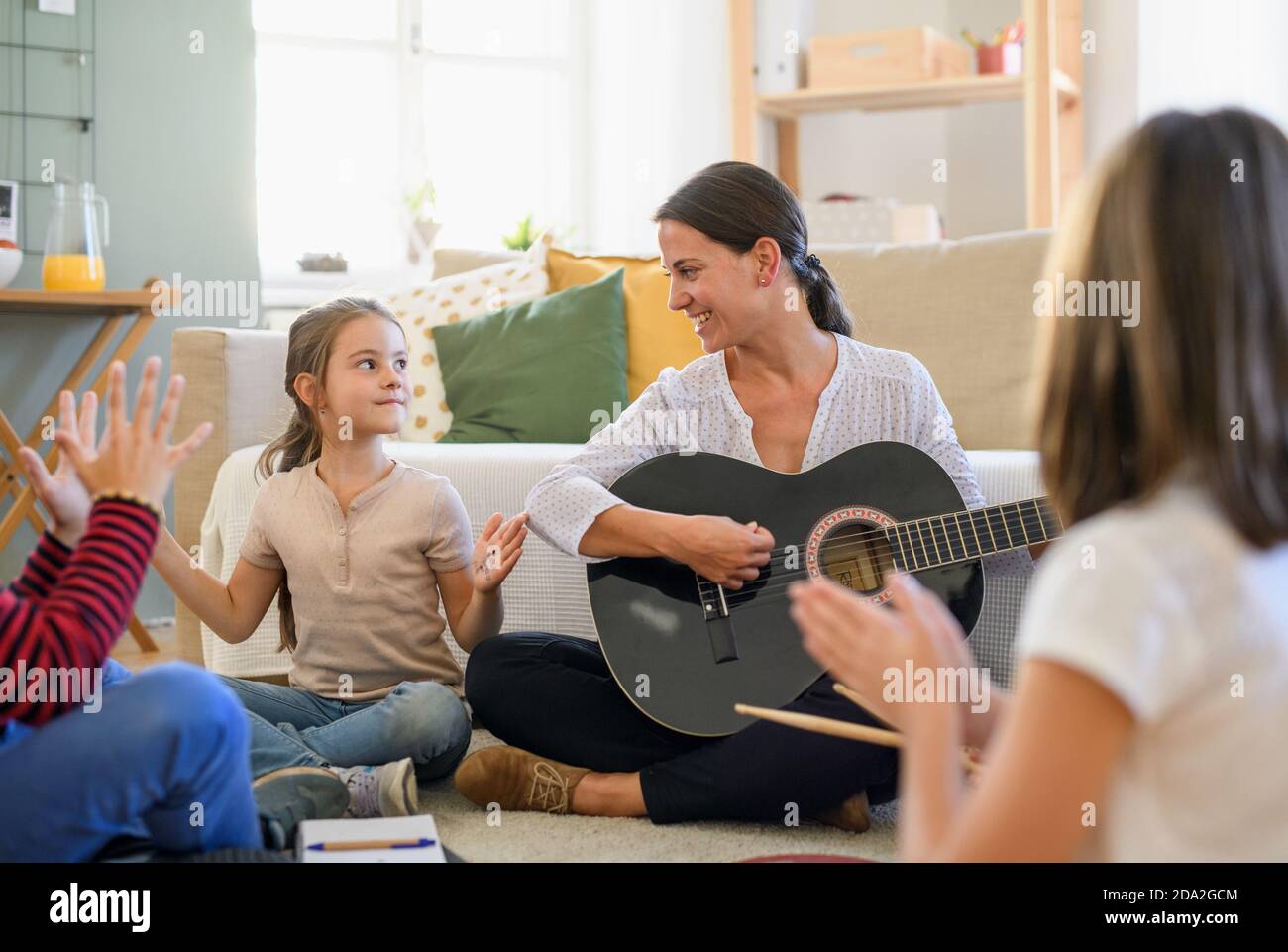 Group of cheerful homeschooling children with teacher having music lesson indoors, coronavirus concept. Stock Photo