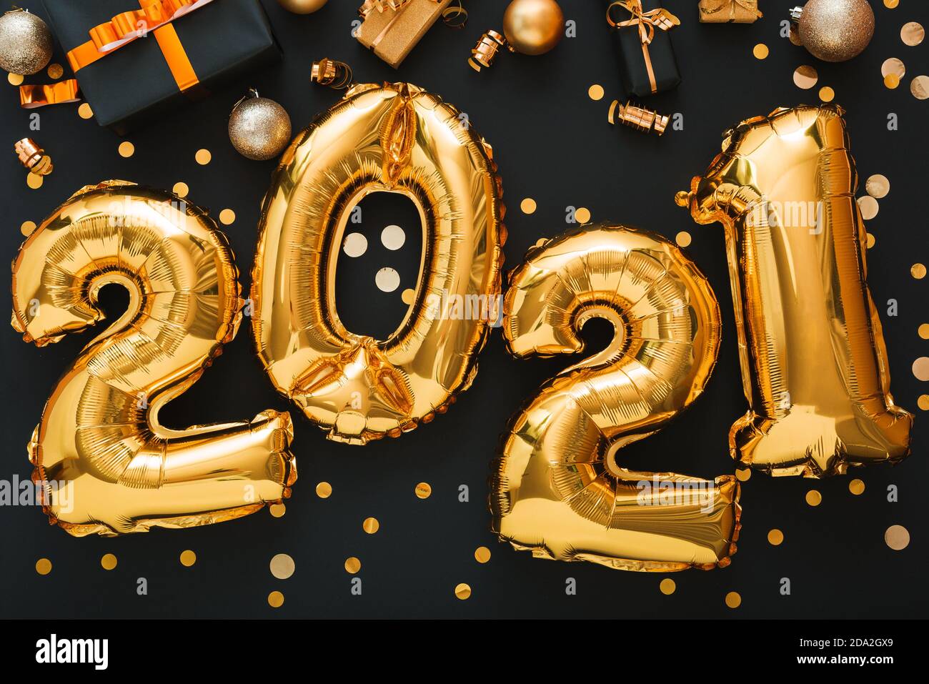 2021 balloon gold text on black background with golden confetti, Christmas gift boxes festive decor. Happy New year eve composition with gold foil bal Stock Photo