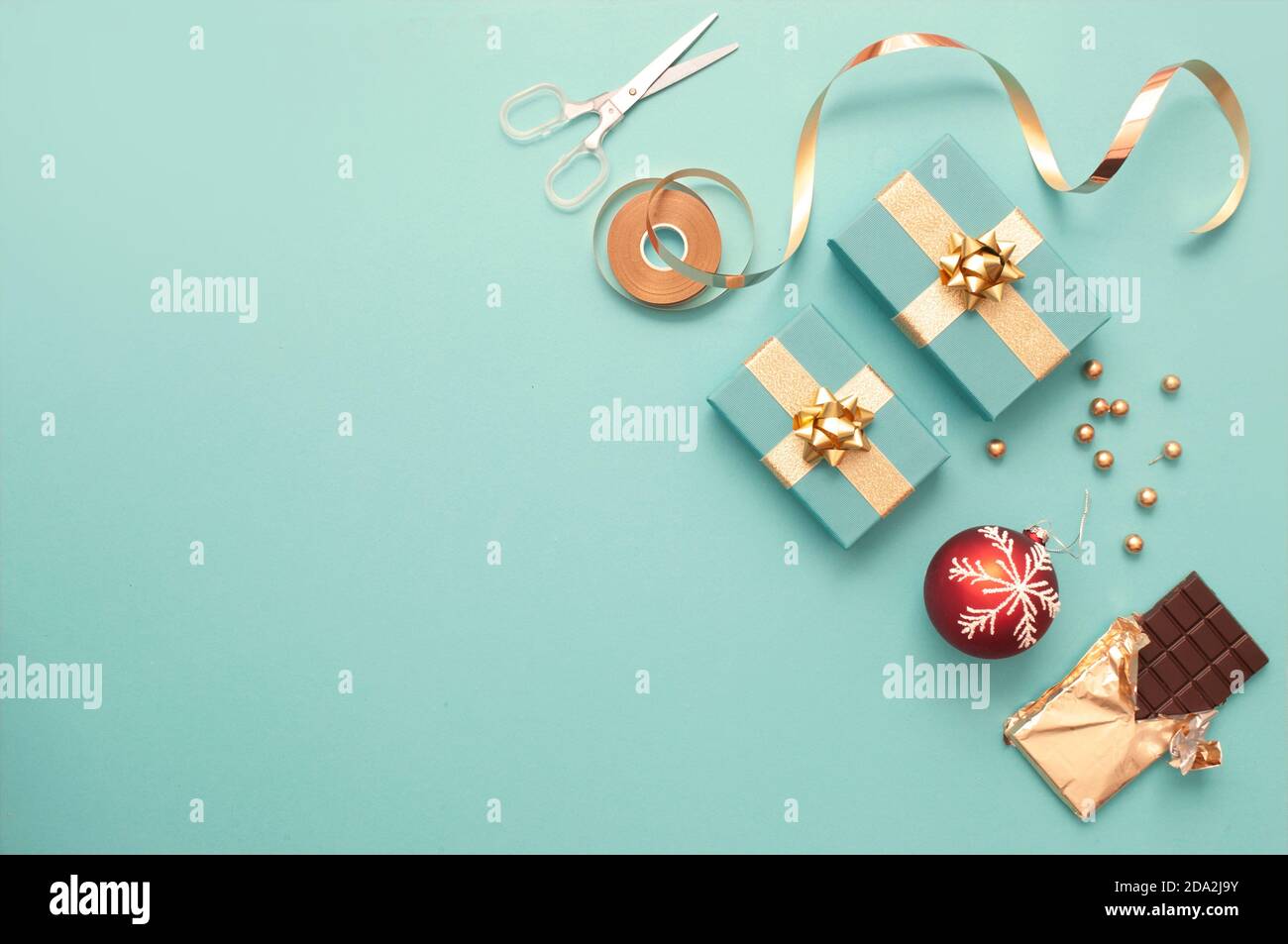 Top view of gift boxes wrapped in gold, baubles, chocolate bar and