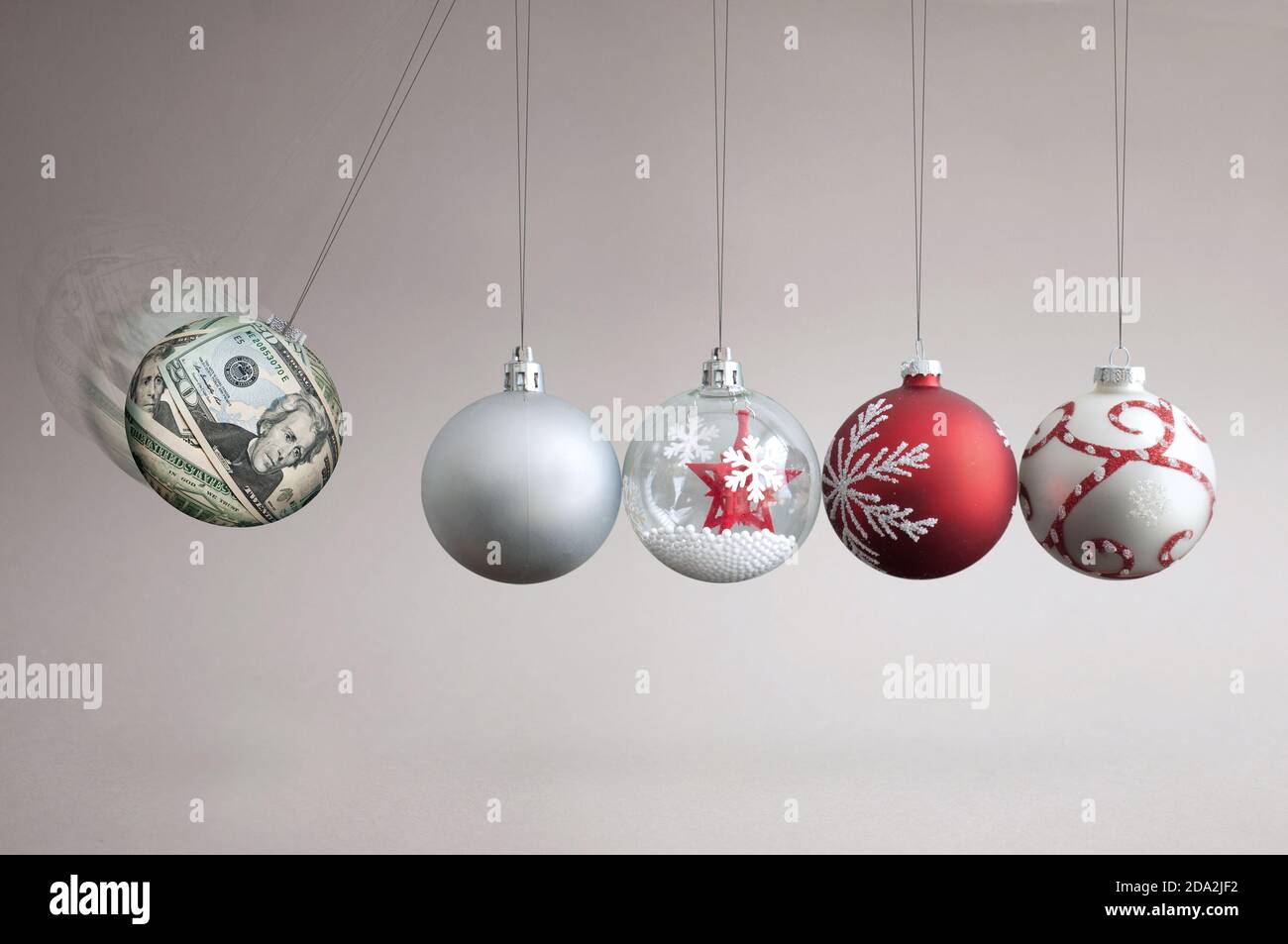 Dollar bauble colliding into christmas ornaments, seasonal shopping budget and balancing finances concept Stock Photo