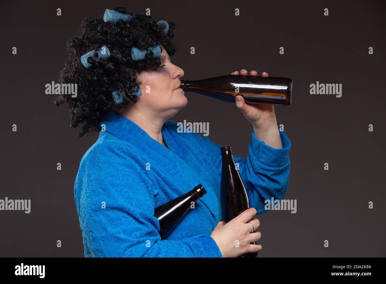 Lonely middleaged woman drinking beer and vodka from a glass tumbler