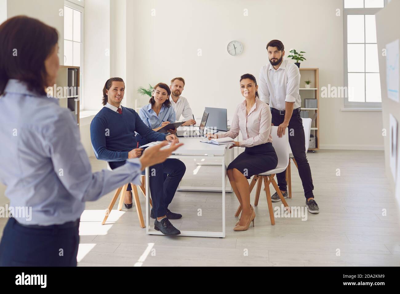 Group of business people in office looking at woman colleague presenting new project or startup idea Stock Photo