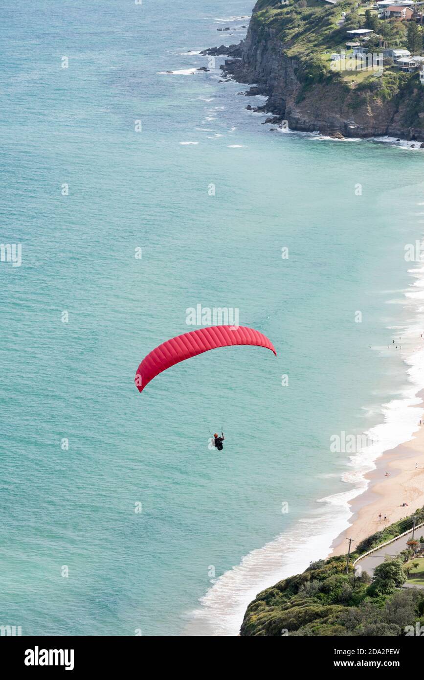 Looking down to Stanwell Park Beach and a paraglider flying, from the popular launch point of Bald Hill, Stanwell Tops, New South Wales, Australia Stock Photo