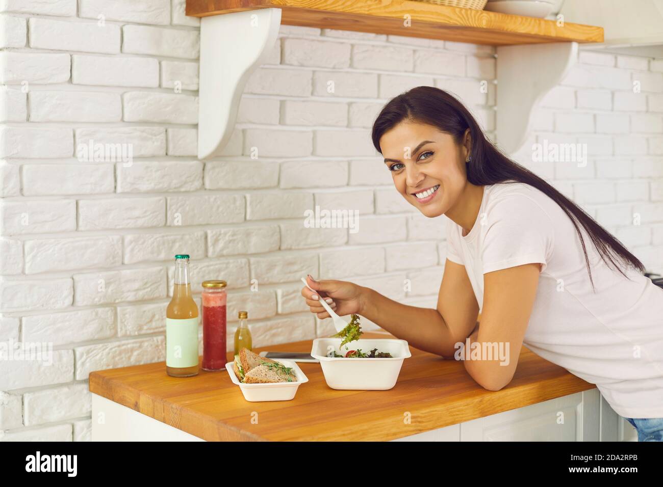 Portrait of happy woman eating lunch salad and takeaway food delivered by delivery service. Stock Photo