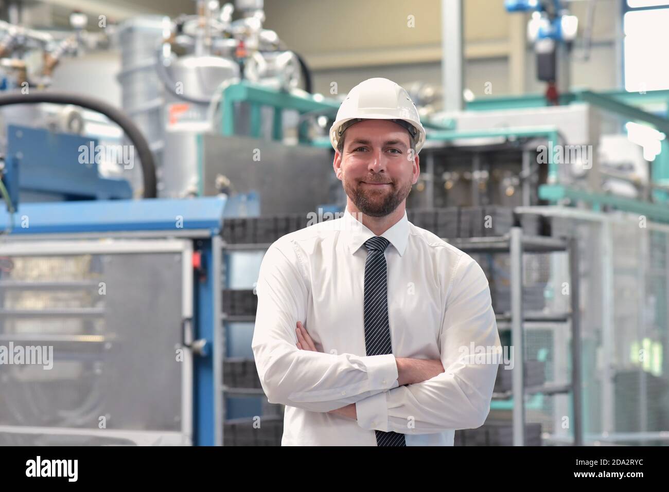 portrait of a successful smiling businessman/ engineer on site in an industrial factory with helmet Stock Photo
