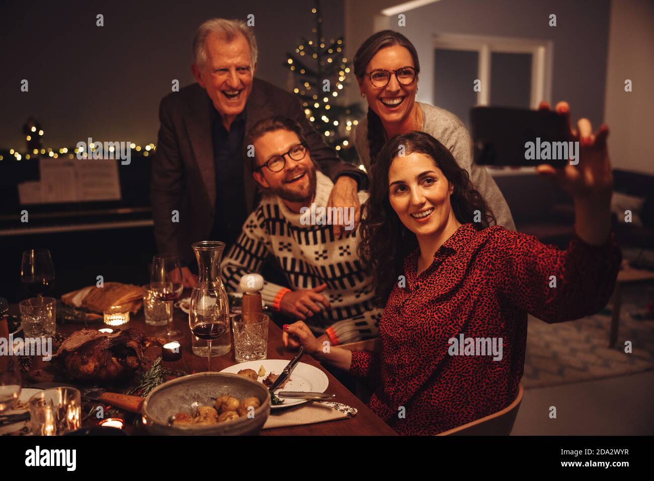 Woman taking selfie with family during thanksgiving dinner. European family taking selfies on christmas eve. Stock Photo