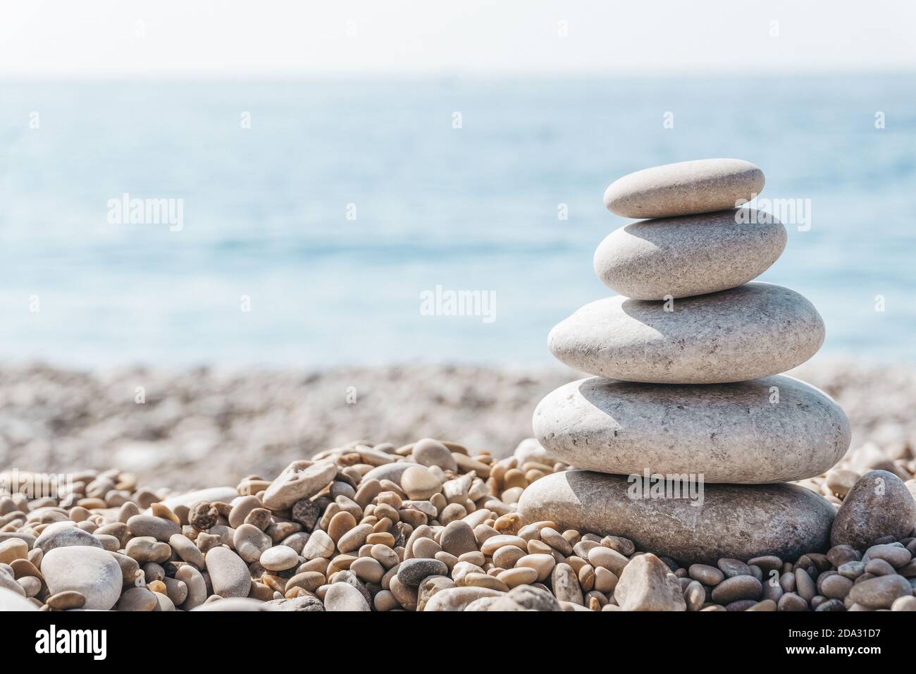 Zen relax background. A pyramid of stones on the beach in clear sunny weather. Background for meditation, yoga and massage Stock Photo