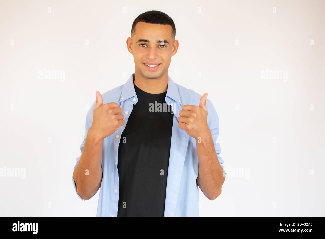 Portrait of cheerful man in basic clothing smiling and showing thumbs ...