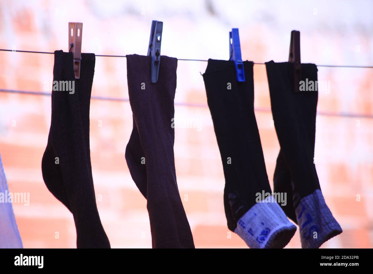 black socks hanging with brick wall background , winter twice pair of socks hanged on clothesline Stock Photo