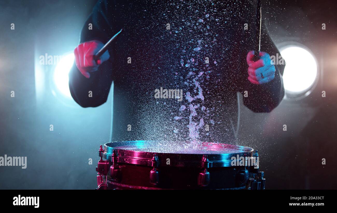 Freeze motion of drummer hitting drum with water splashes, isolated on black background Stock Photo