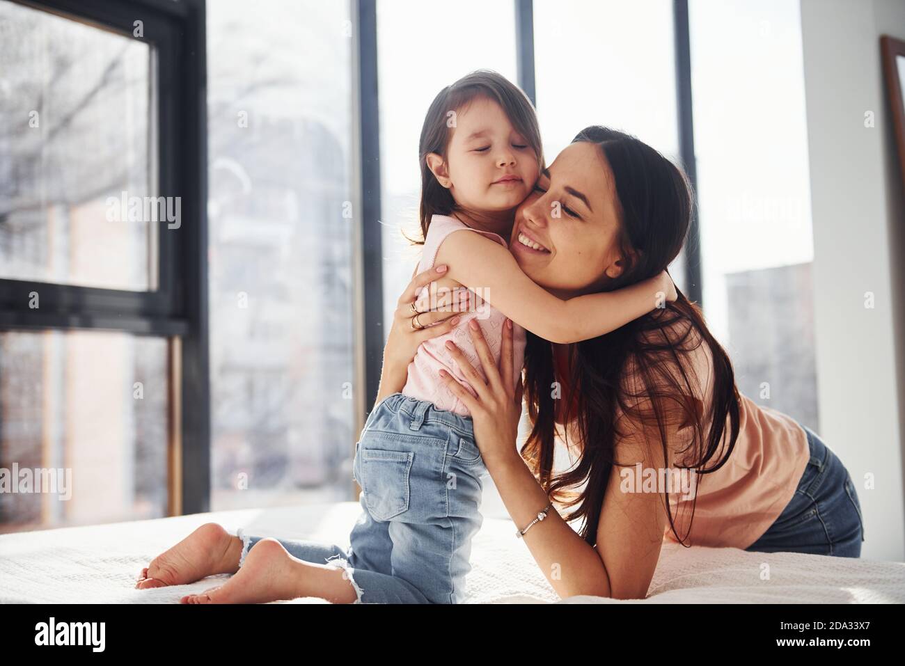 Young mother with her daughter embracing each other on bed Stock Photo