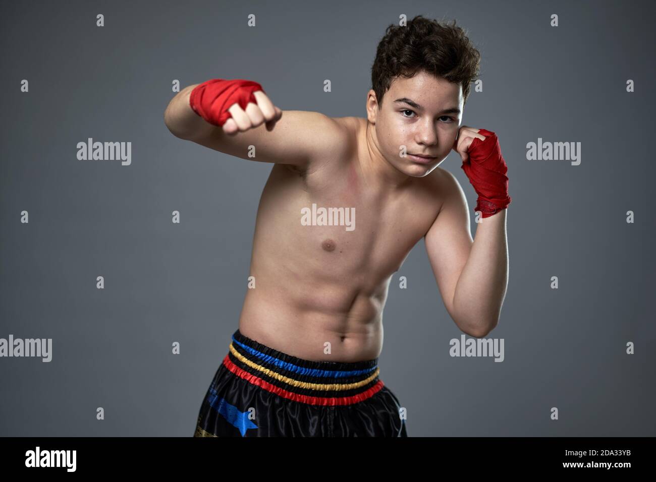 Young kickboxer with hands wrapped training in shadow boxing against