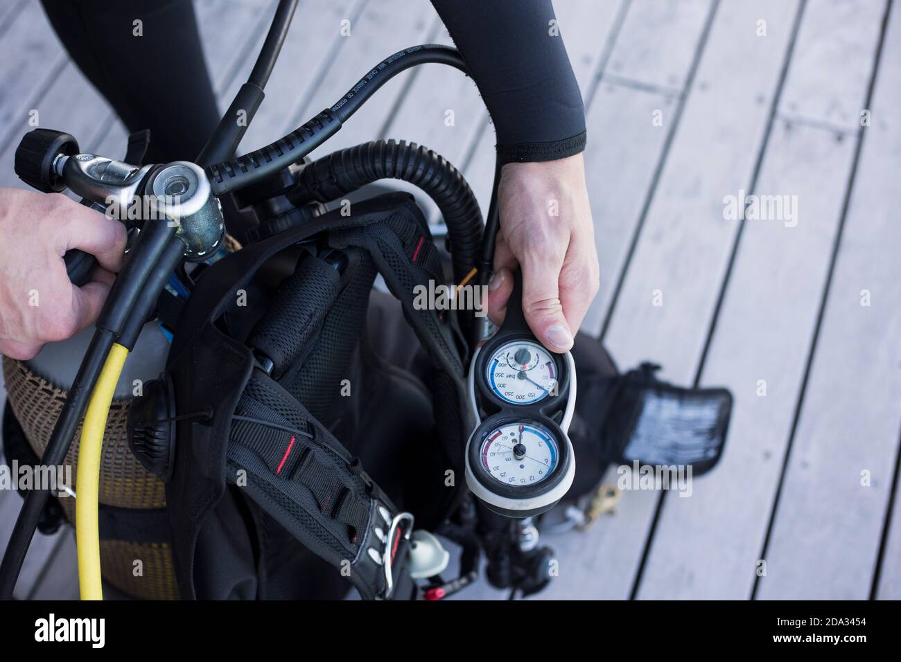 Scuba diver kitting up and checking the pressure gauge, close up of