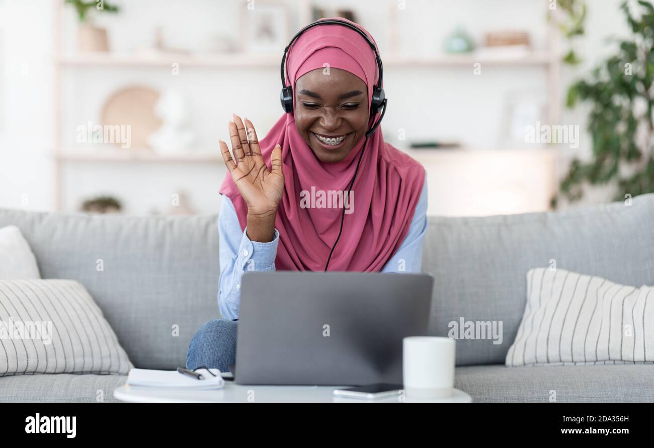 Teleconference. Smiling black muslim woman in headset making video call ...