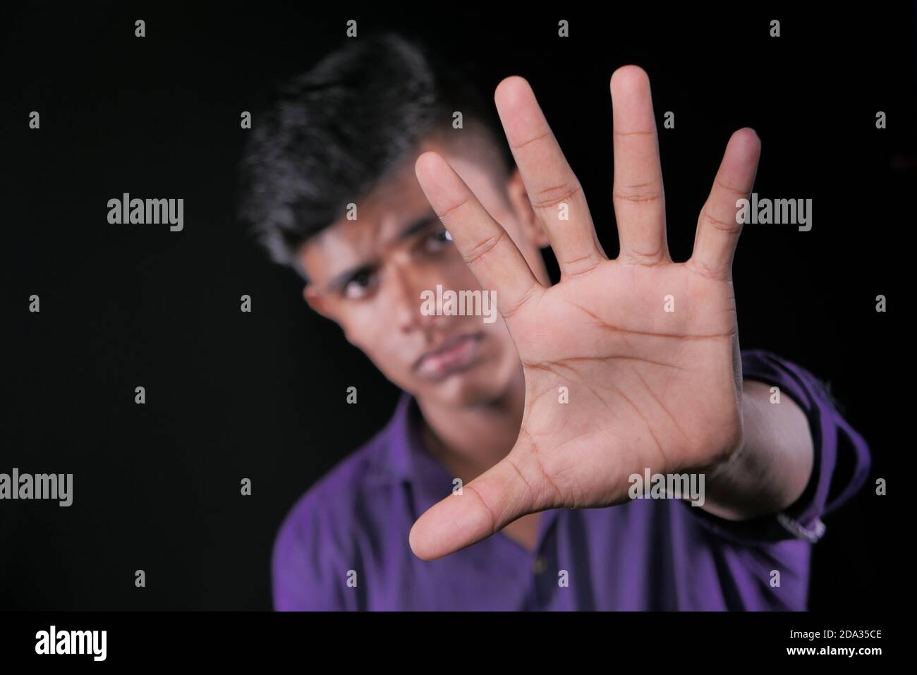 young man show stop sigh isolated in black  Stock Photo