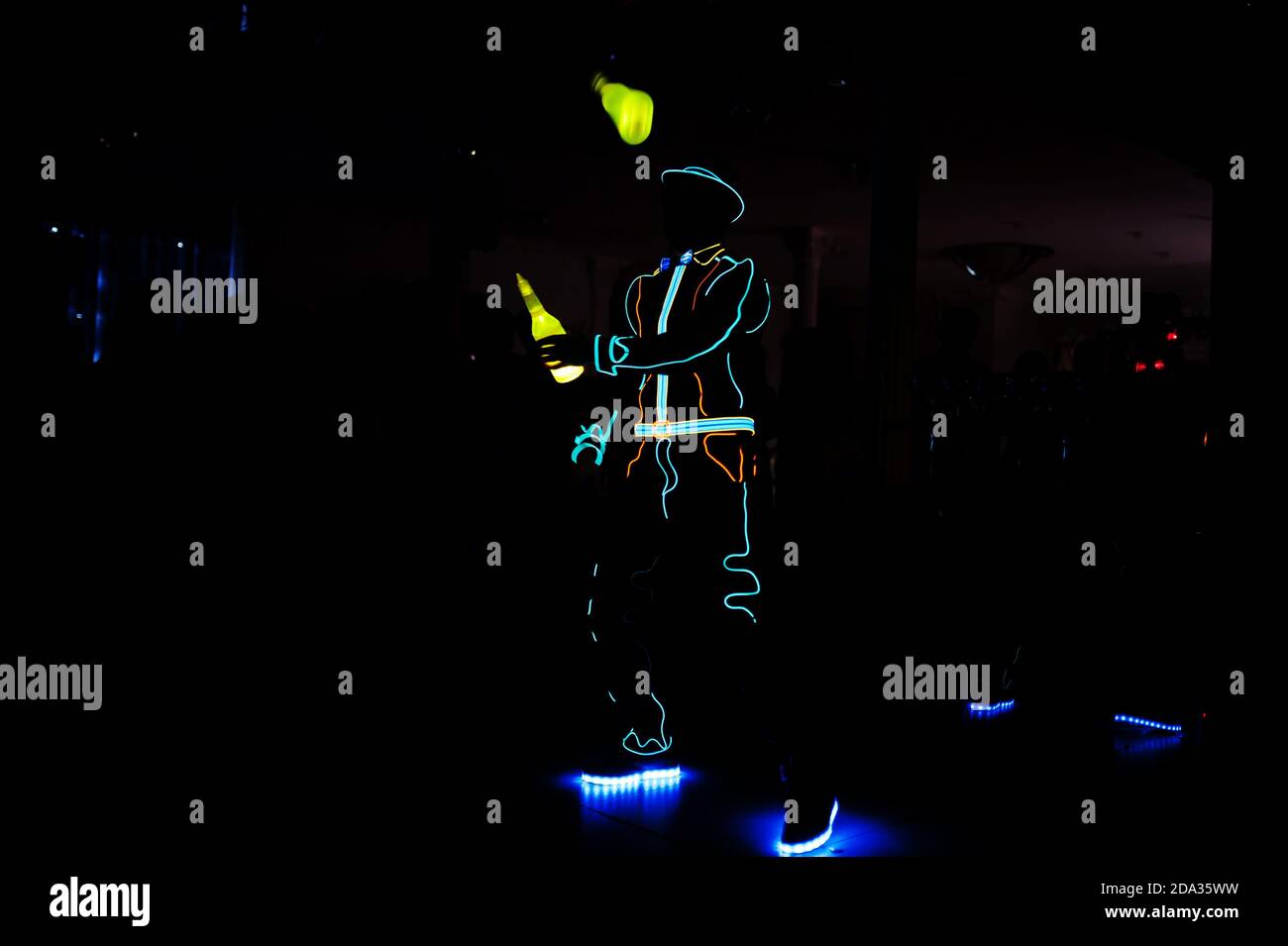 Professional barman and led light show. Silhouette of modern bartender shaking drink at night cocktail bar. Stock Photo