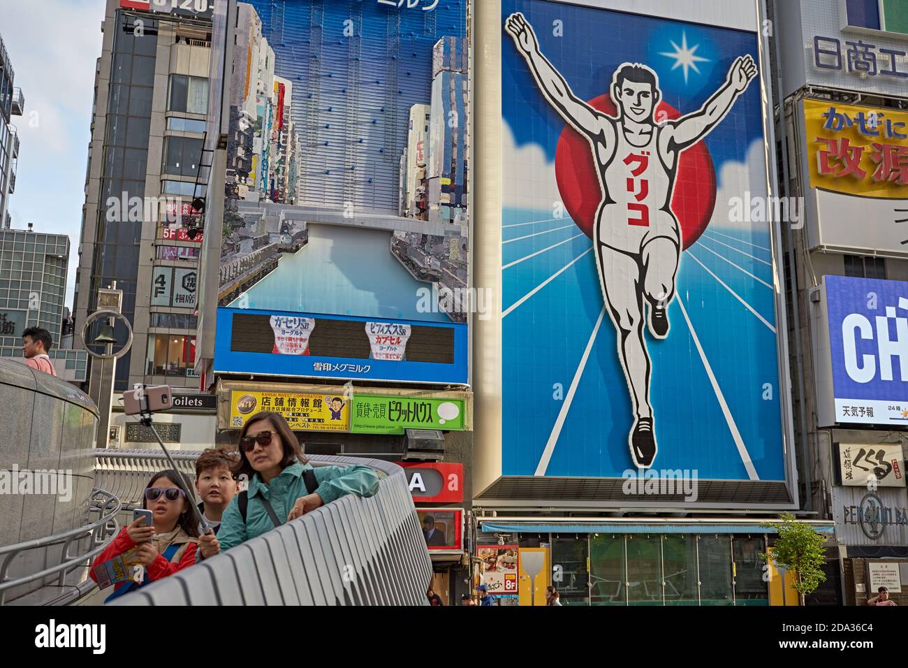 Osaka, Japan, April 2018. People making selfies in front of the luminous sign of the Glico running man in Dotombori, the most famous landmark of the c Stock Photo
