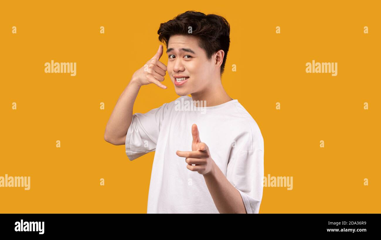 Man pointing index finger on camera, doing phone gesture Stock Photo