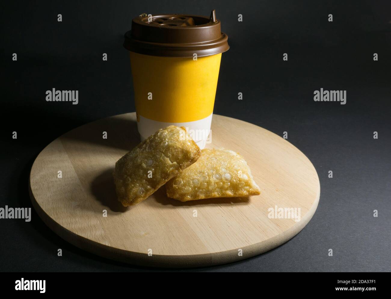 Glass of coffee and fried pie on a wooden stand on a black background Stock Photo