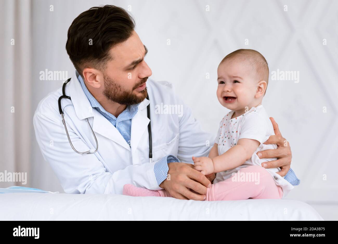 Male Doctor Pediatrician Examining Little Baby Girl In Clinic Indoors Stock Photo