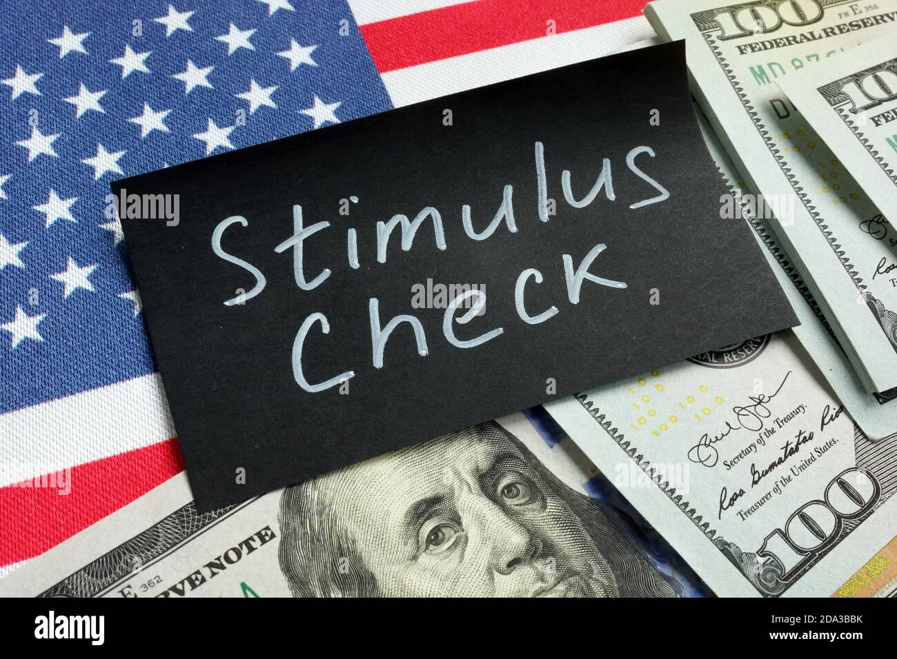 Stimulus check words, money and USA flag. Stock Photo