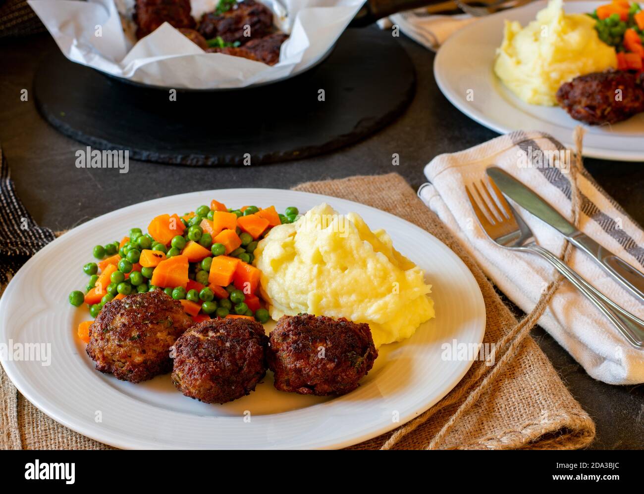 fried meatballs with mashed potatoes and buttered peas and carrot vegetables served on a plate Stock Photo