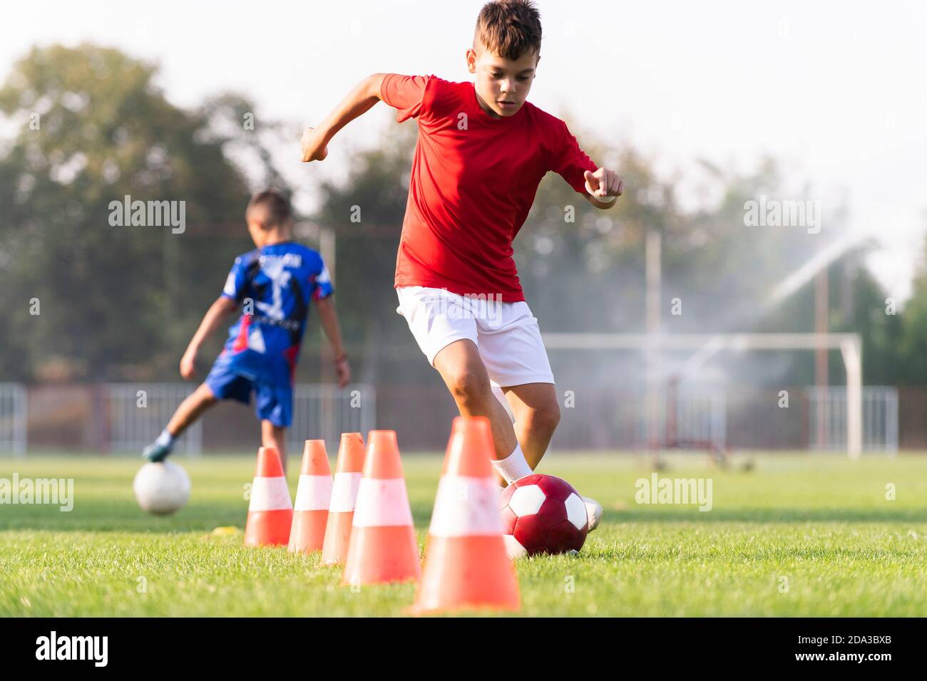 boy in sportswear trains football on soccer  field and learns to circle the ball between train Stock Photo