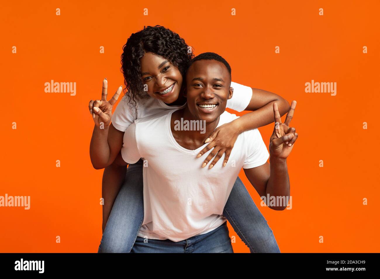 Happy black lovers posing on orange studio background Stock Photo