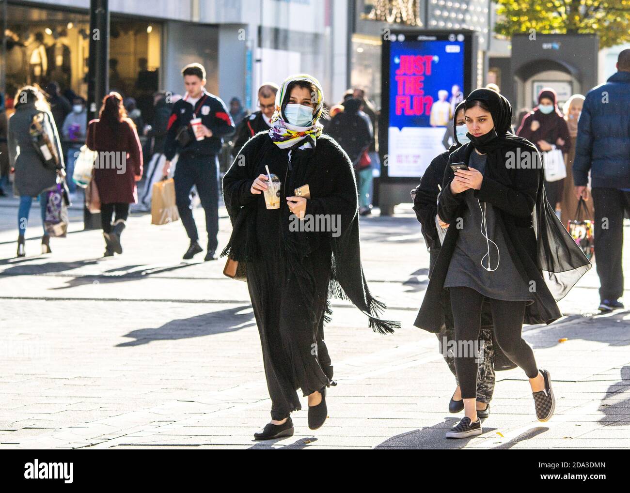 Shoppers wearing facemasks on the eve of the UK winter lockdown in November, Birmingham, UK. Just the Flu? sign in the background Stock Photo