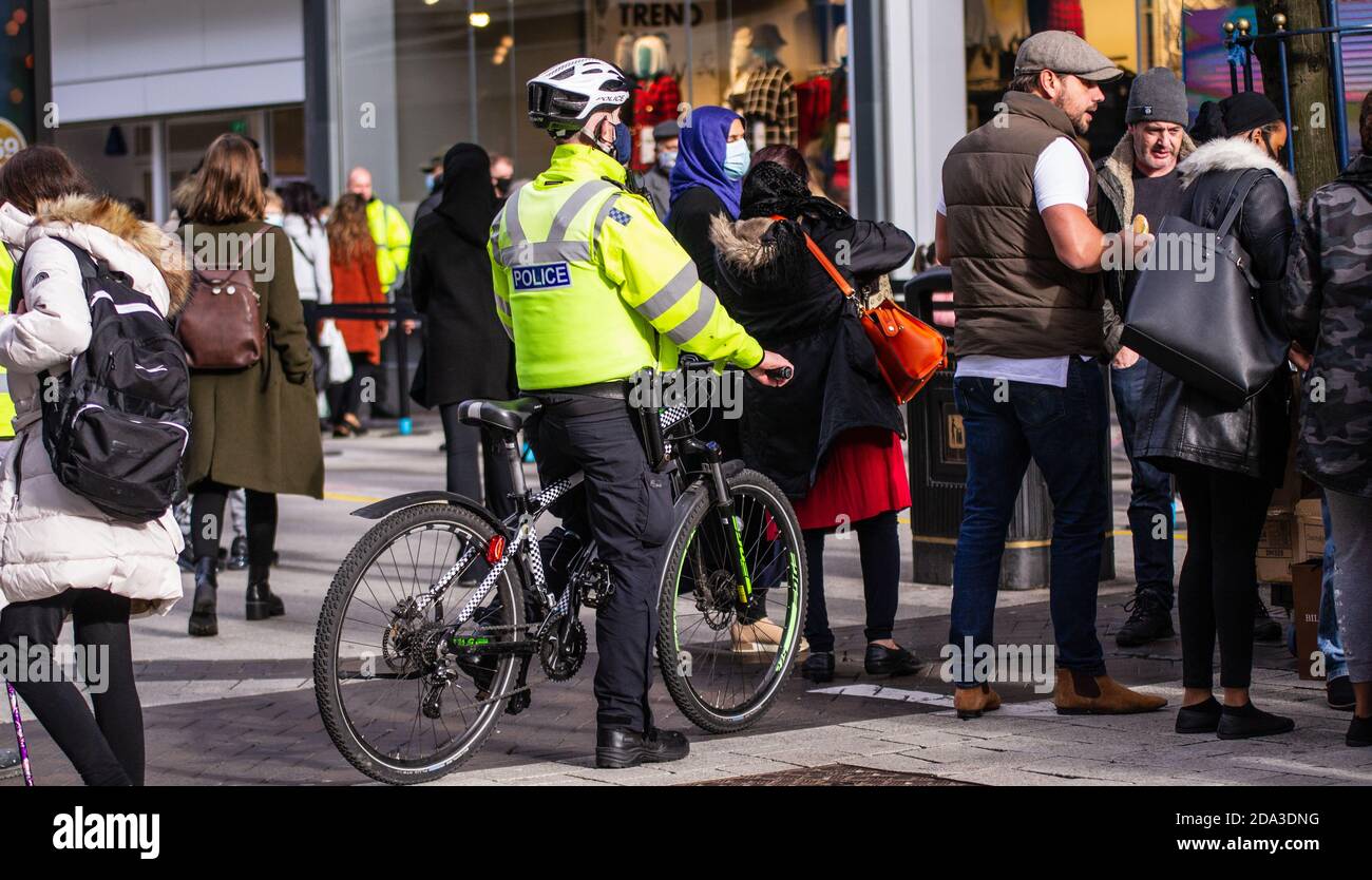 Police officer riding bike through Birmingham High Street crowd Stock Photo