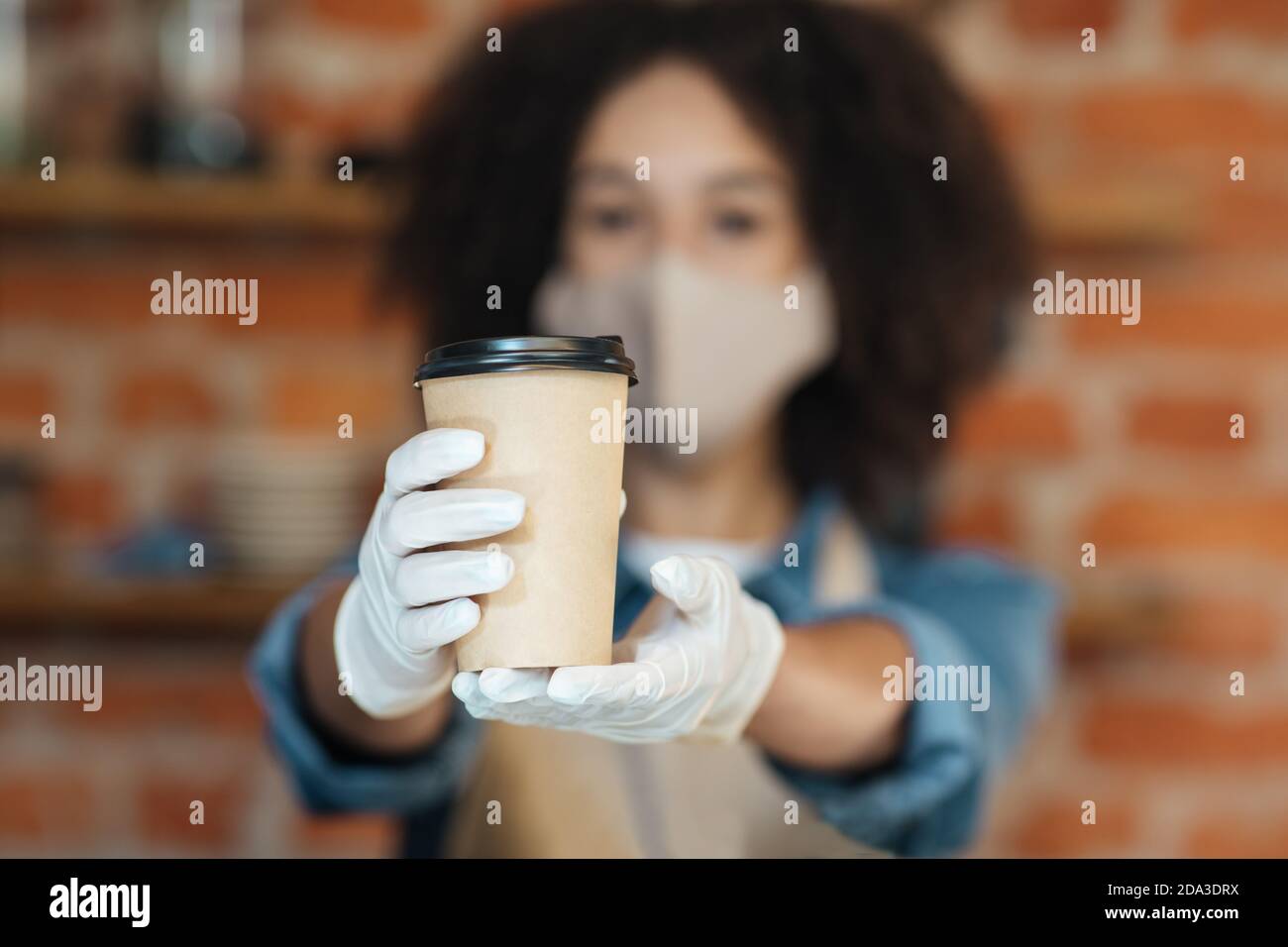 Woman with face mask serving coffee at Covid-19, social distancing, small coffee shop business and preventing virus Stock Photo