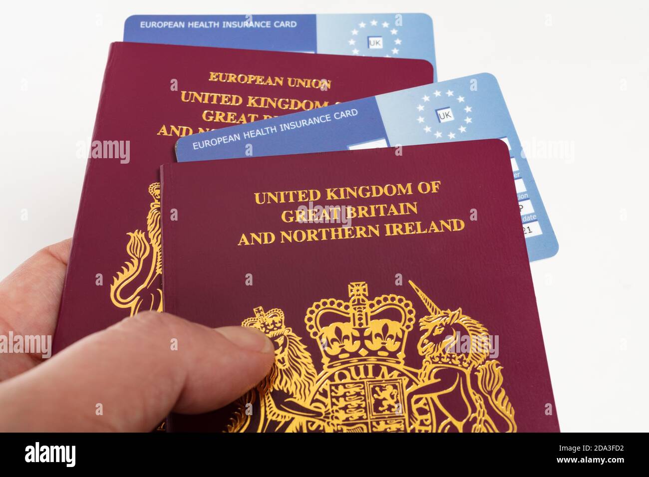Hand holding United Kingdom British passports and EHIC European Union Health Insurance Cards, Stock Photo