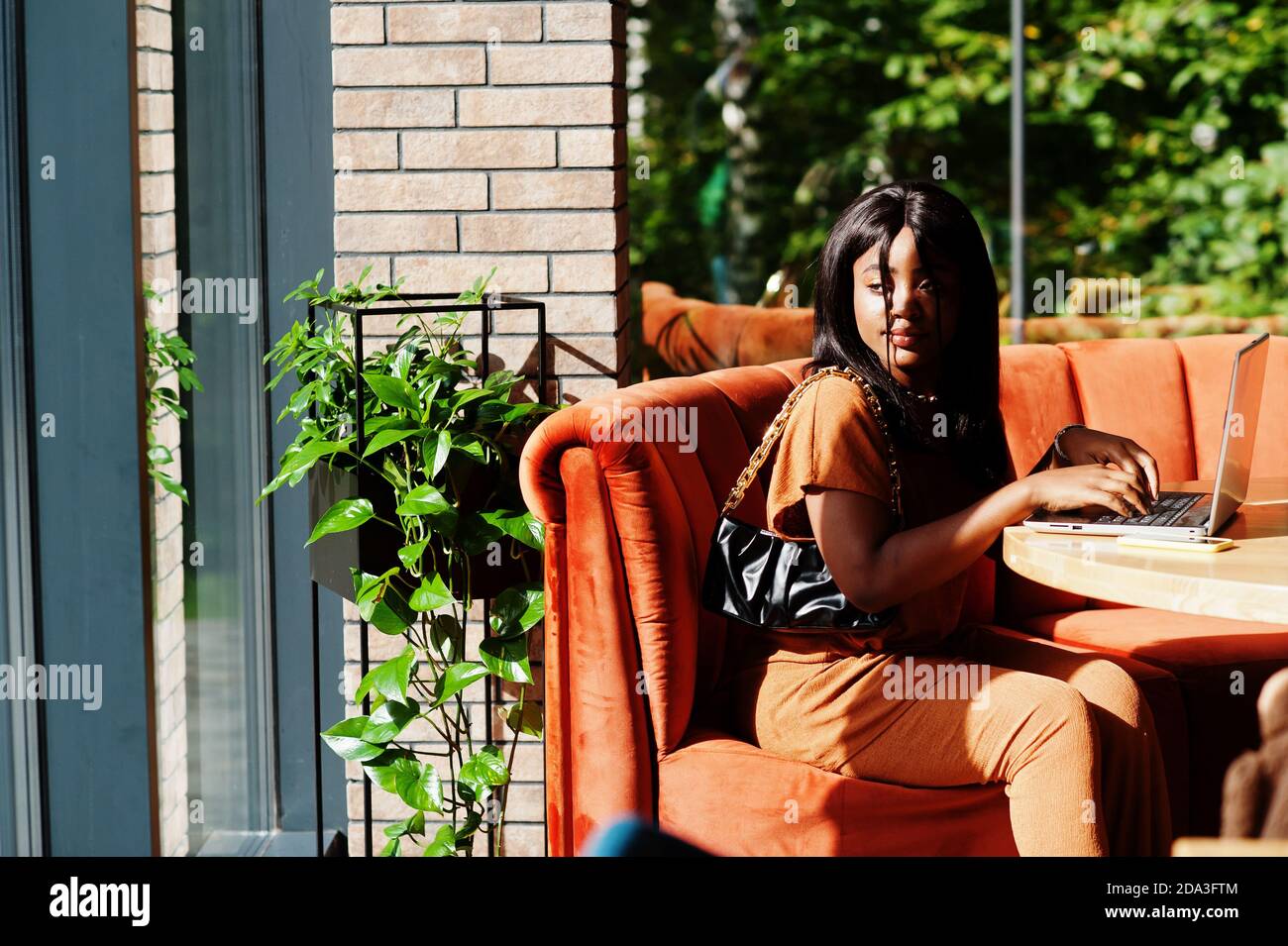 Portrait of beauty young black woman, wear orange outfit, sitting with ...