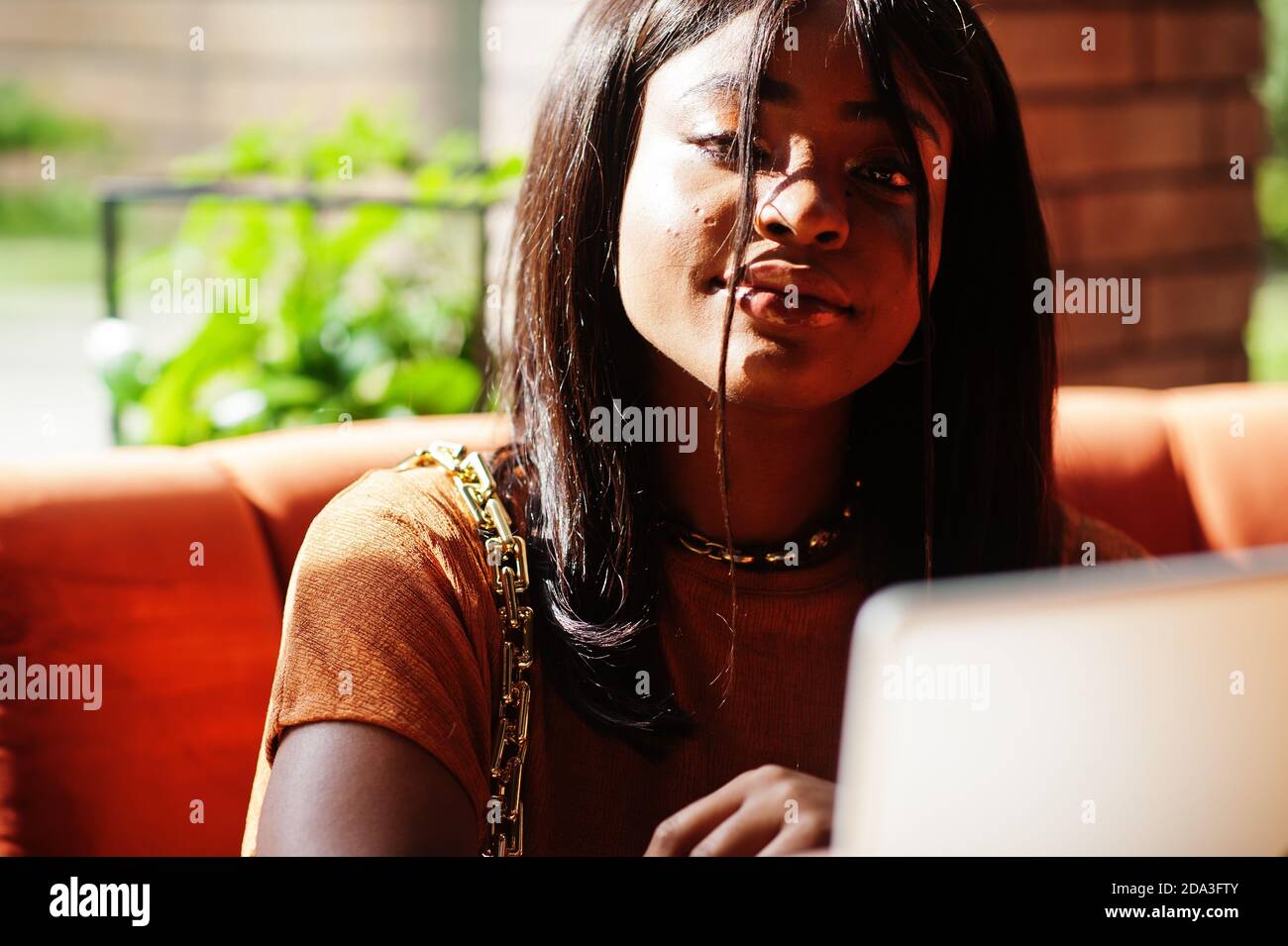 Portrait of beauty young black woman, wear orange outfit, sitting with ...