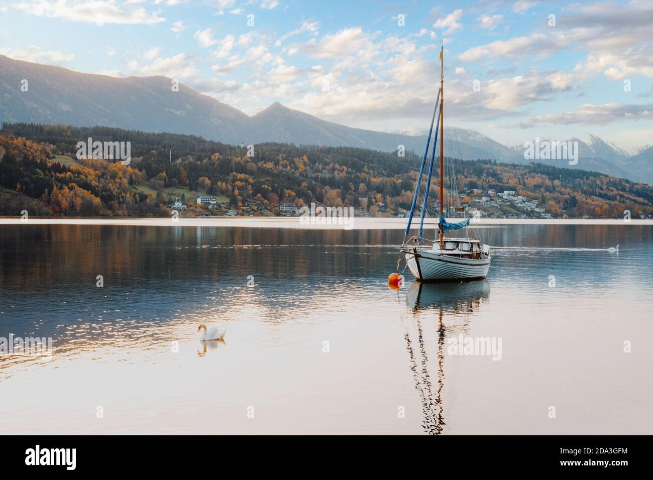 Sailboat at the idyllic lake Millstaetter See in Carinthia, Austria. Beautiful alpine lake in autumn with snow covered mountains in the background. Stock Photo