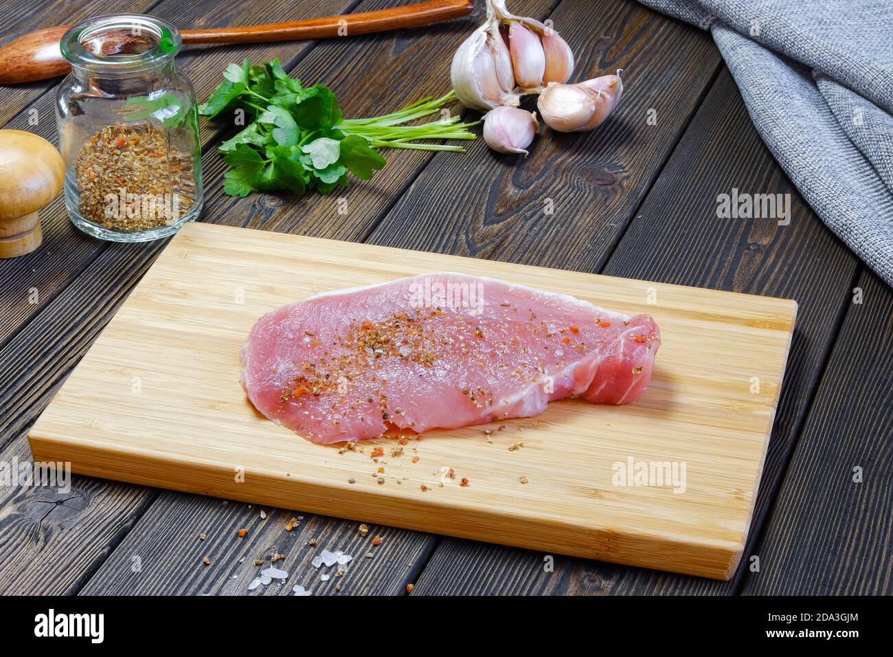Juicy pieces of steak lie on the cutting Board. Escalope is prepared for frying in a frying pan. Near seasonings and ingredients for cooking Stock Photo