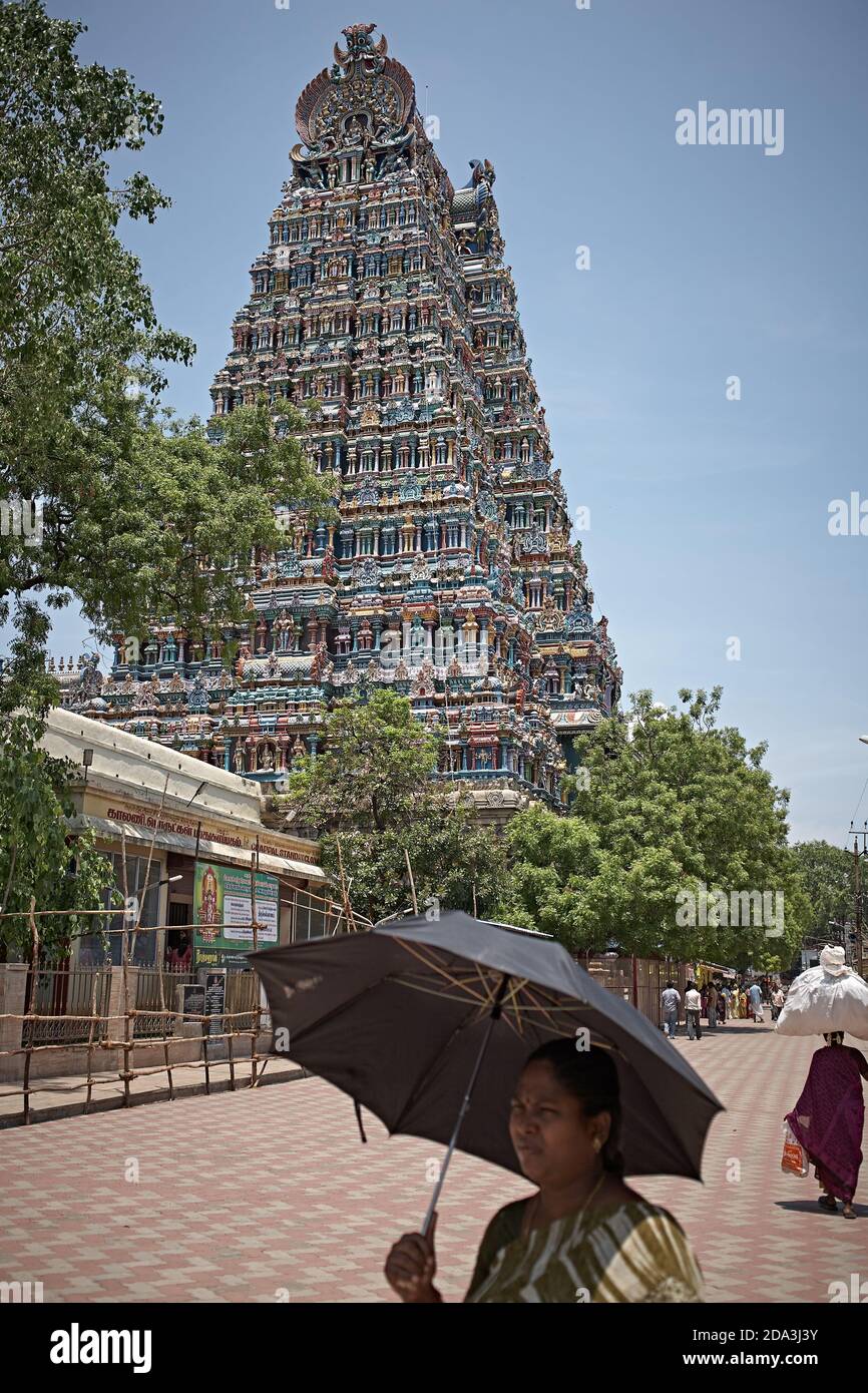 Madurai, India, May 2012. A woman with an umbrella passes in front of Meenakshi Temple. Stock Photo