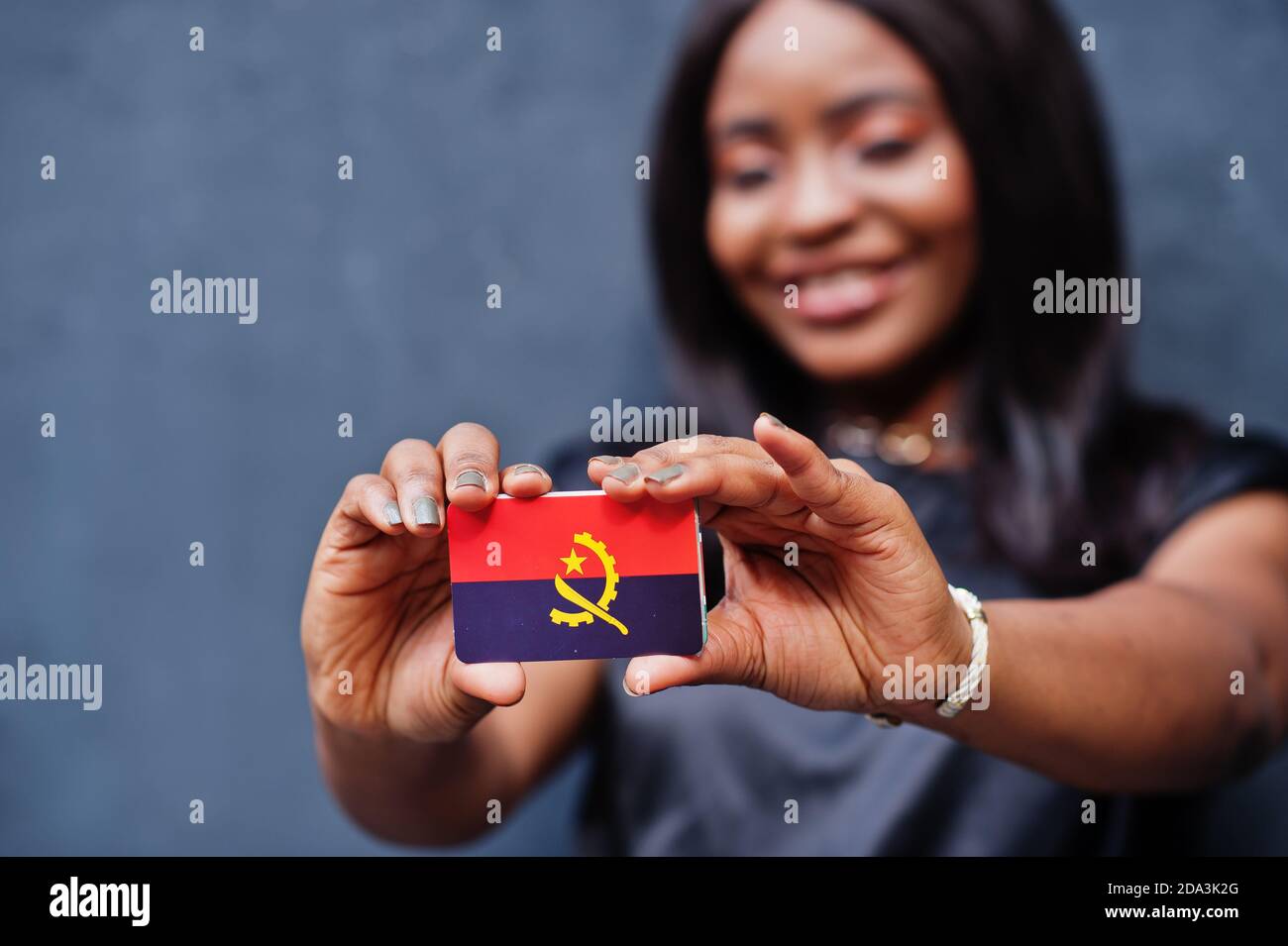 African woman hold small Angola flag in hands. Stock Photo