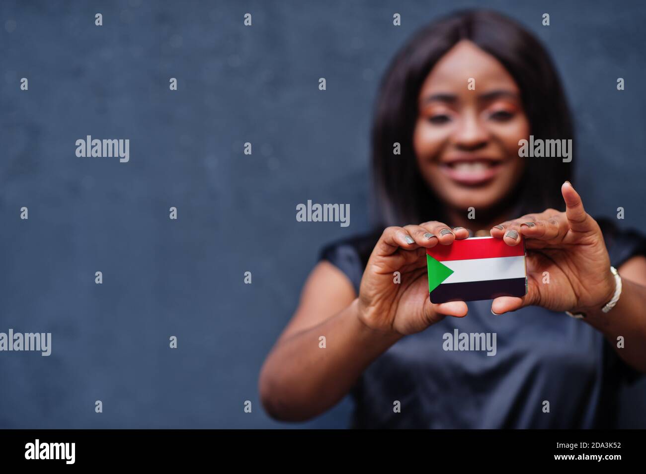 African woman hold small Sudan flag in hands. Stock Photo