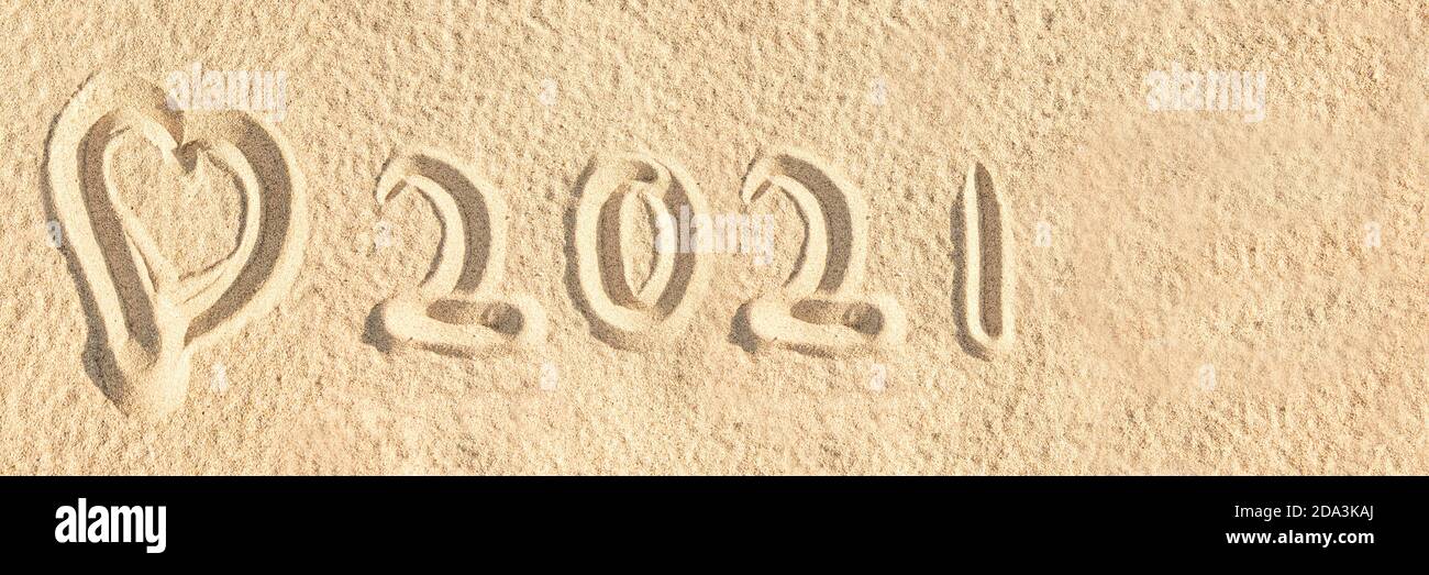 Year 2021 written in the sand of a beach with a heart, travel panoramic banner Stock Photo
