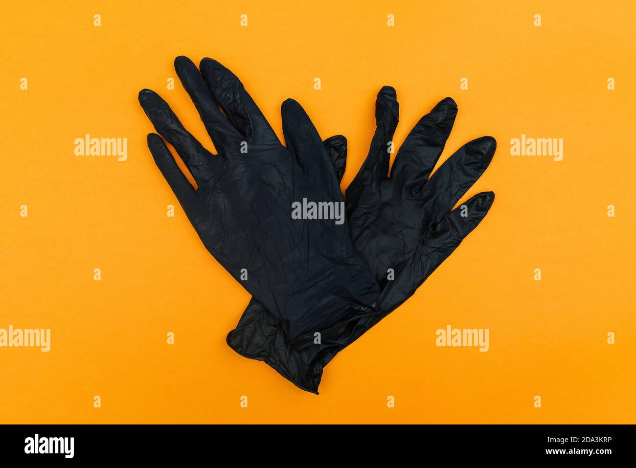 Black disposable gloves isolated on orange background. Hand protection from coronavirus, hygiene. Top view, flat lay Stock Photo