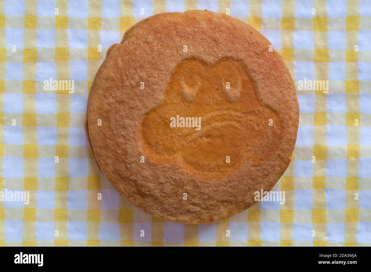 Cadbury Freddo Face Cake soft cakes with a delicious choc chip filling with different expressions on yellow and white checked serviette napkin Stock Photo