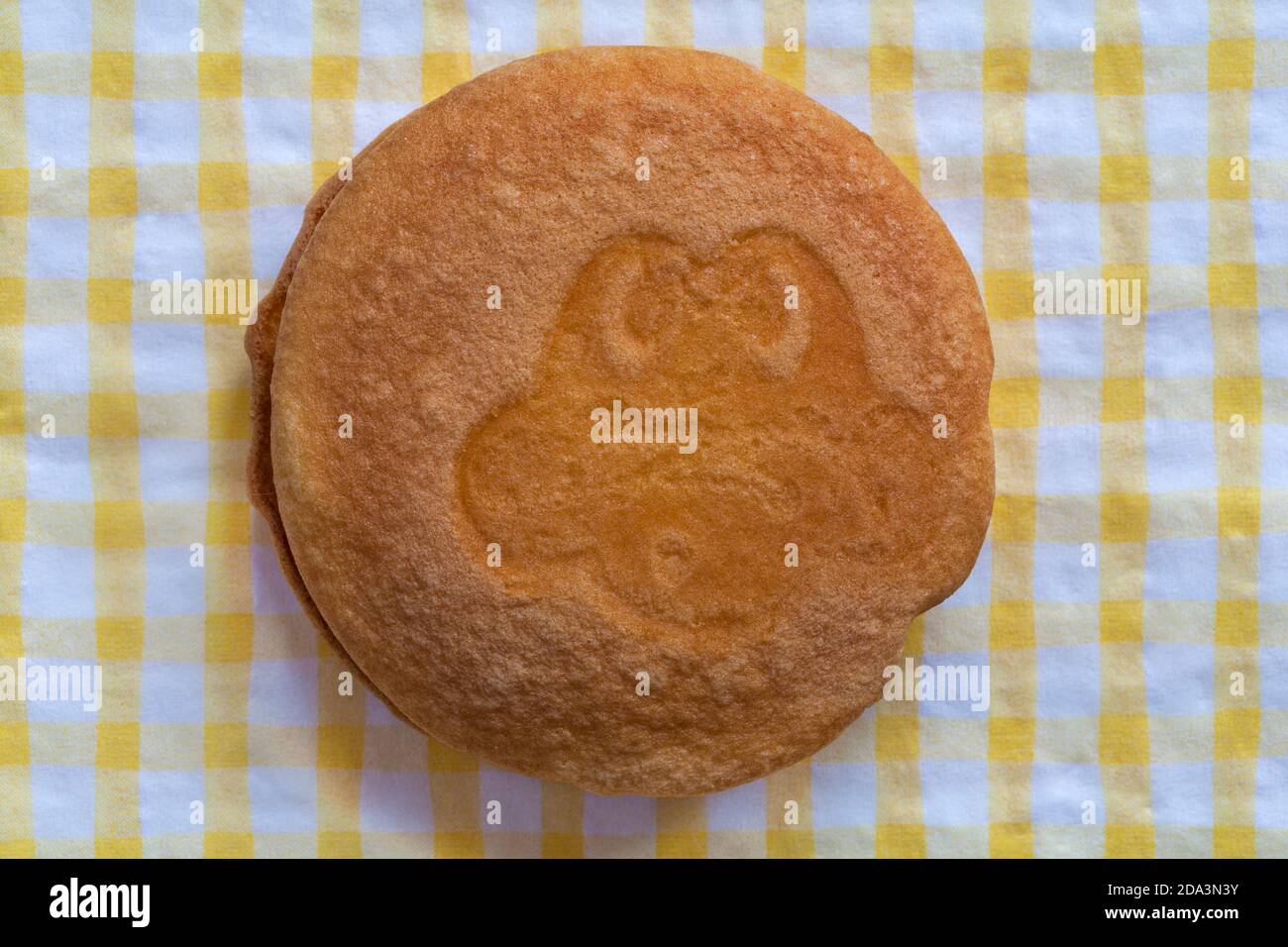 Cadbury Freddo Face Cake soft cakes with a delicious choc chip filling with different expressions on yellow and white checked serviette napkin Stock Photo