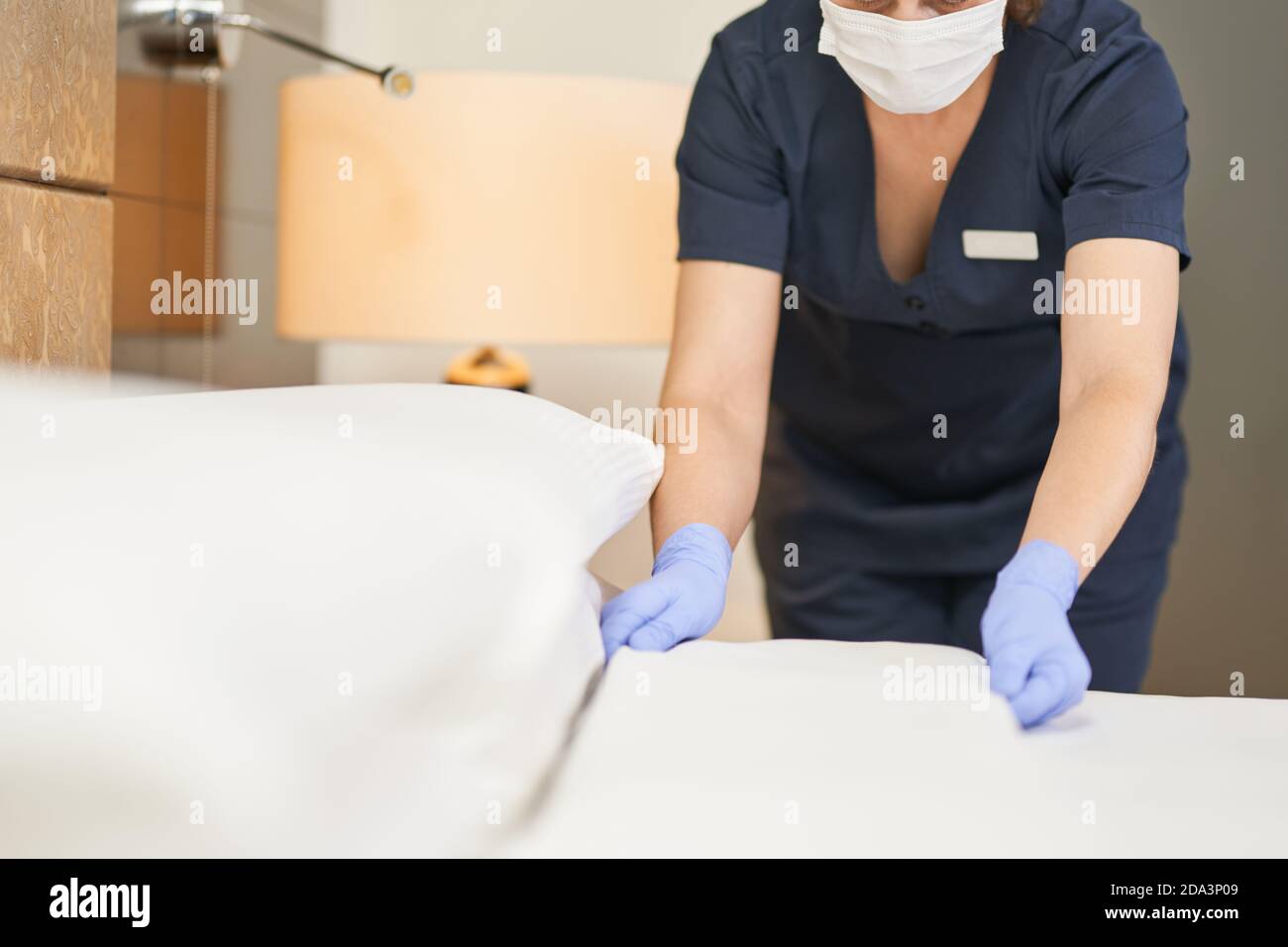 Cropped photo of housemaid making bed and changing bedding in guest room in hotel. Hotel service concept Stock Photo