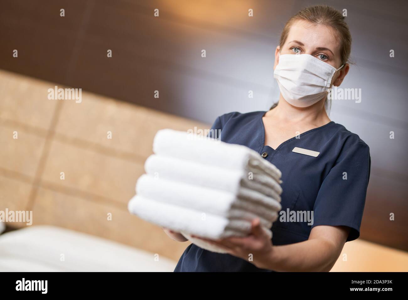 Female housemaid standing with fresh clean towels while cleaning the hotel room. Hotel service concept. Copy space Stock Photo