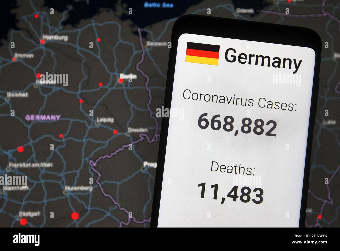 In this photo illustration, the statistics of Covid-19 coronavirus spread in Germany by worldometers website seen displayed on a smartphone with a background of a map by the Center for Systems Science and Engineering (CSSE) at Johns Hopkins University (JHU) showing the Covid-19 coronavirus global spread on a computer screen.The Covid-19 global cases pass 50 million and 10 million in the U.S., according to internet online trackers of the coronavirus spread. Stock Photo
