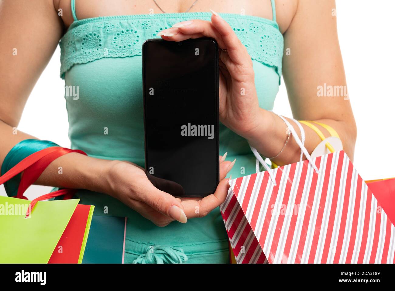 Blank copyspace for advertising on smartphone screen held by adult female model carrying shopping bags as modern consumerism concept isolated on white Stock Photo